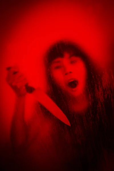 Woman with knife screaming behind stained or dirty window glass — Stok fotoğraf