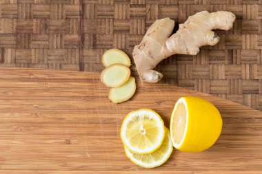 Dilimlenmiş taze zencefil kökü ve limon ahşap kesme tahtası üzerinde