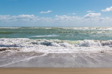 Mavi gökyüzü ve fırtınalı Atlantik Okyanusu.
