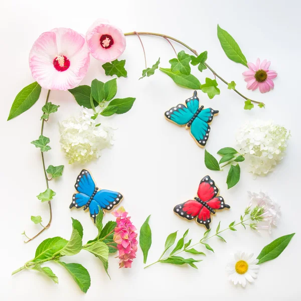 Floral frame with  flowers and homemade butterfly shaped cookies — Stock Photo, Image