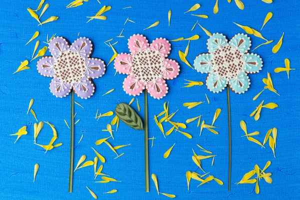 Biscuits en forme de fleurs décorés d'ornements sur fond bleu — Photo