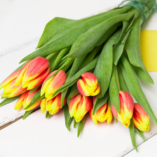 Ramo de tulipanes rojos amarillos sobre fondo de madera —  Fotos de Stock