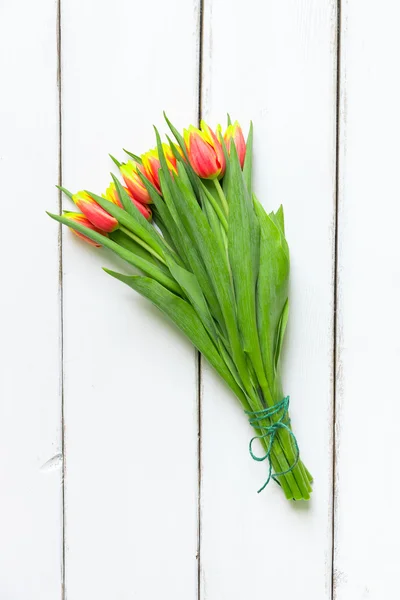 Ramo de tulipanes rojos amarillos sobre fondo de madera —  Fotos de Stock
