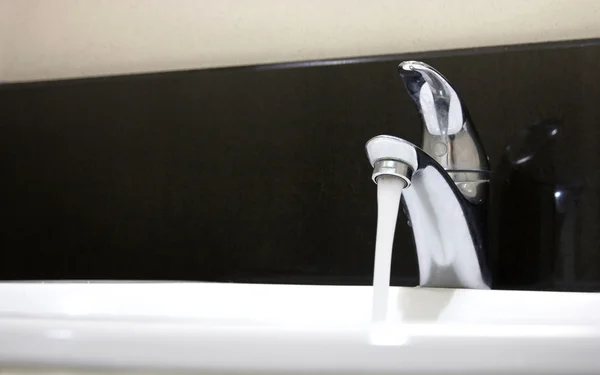 Открытый кран и поток воды в ванной комнате — стоковое фото
