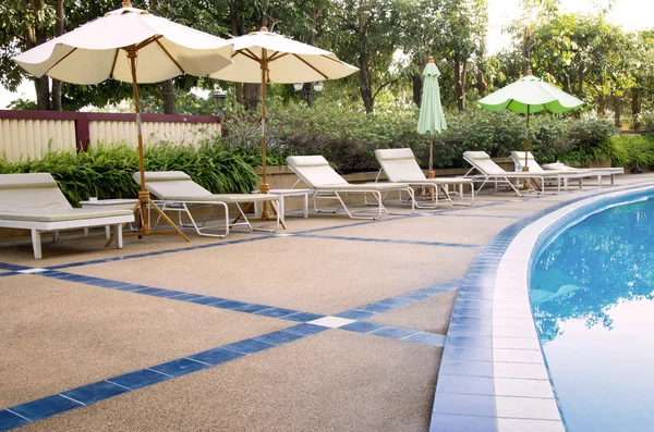 Beach chairs and umbrella on swimming pool — Stock Photo, Image