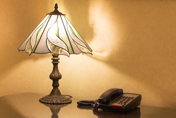 Tischlampe und Telefon auf dem Schreibtisch — Stockfoto