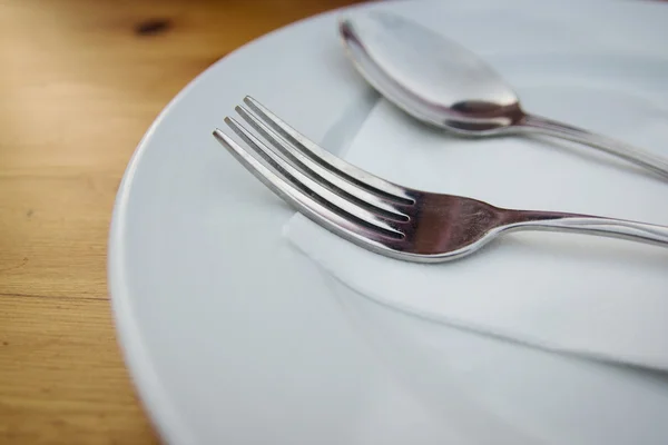 Fourchette et cuillère avec plaque blanche sur table en bois — Photo