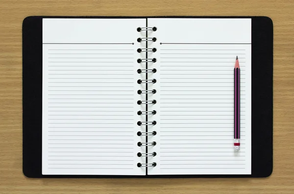 Caderno espiral em branco e lápis sobre fundo de madeira — Fotografia de Stock