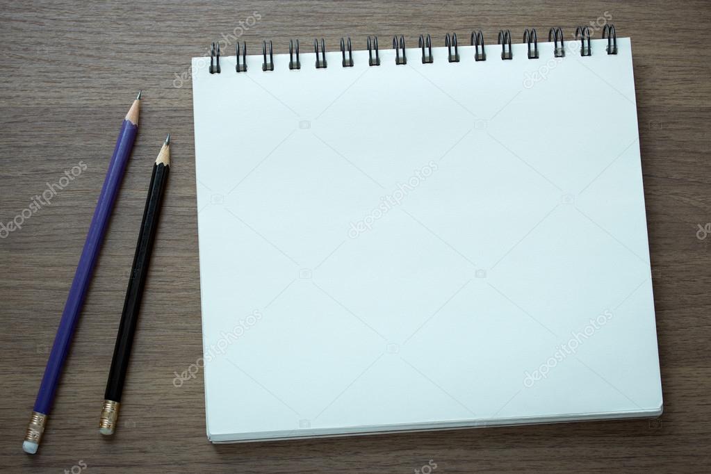 blank spiral notebook and pencil on dark wood background