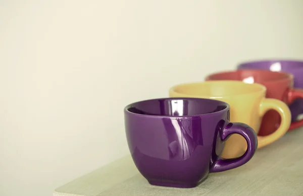 Linha de copos coloridos na mesa de madeira — Fotografia de Stock