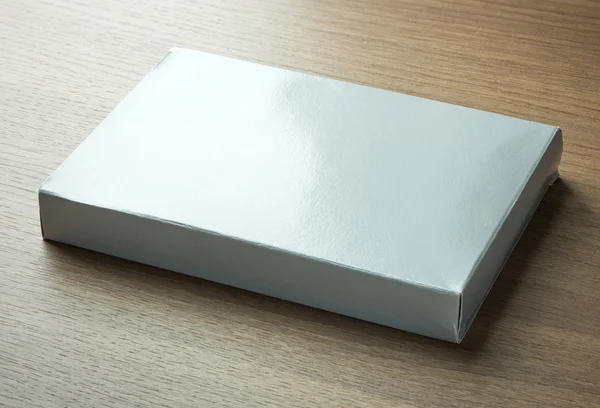 Caixa de papel cinza em branco no fundo de madeira escura — Fotografia de Stock