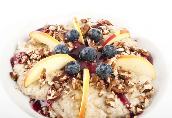 Harina de avena con manzanas, bayas negras, frutos secos y cobertura Fotos De Stock