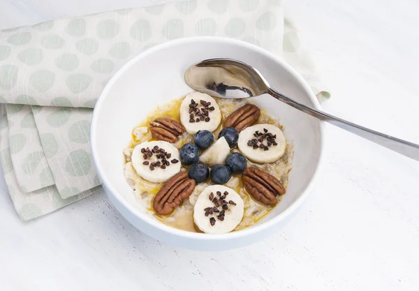 Haferbrei mit Banane, Nüssen, Belag und Schokoladenbröseln lizenzfreie Stockfotos