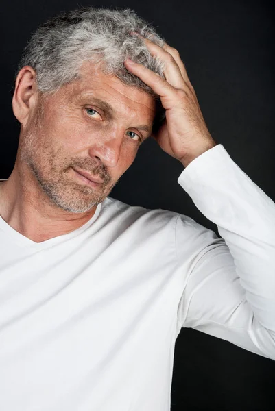 Ritratto di un uomo di mezza età dai capelli grigi su sfondo nero — Foto Stock