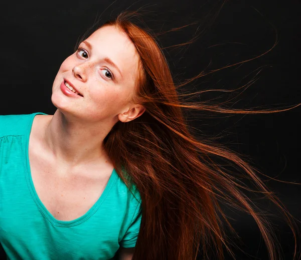 Mladá dívka s tekoucí červené vlasy na černém pozadí — Stock fotografie