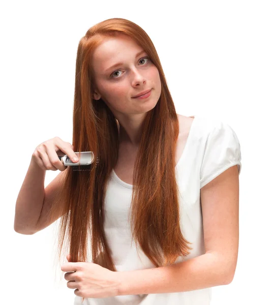 Young red-haired girl combing her long hair. Isolated on white b — Stock Photo, Image