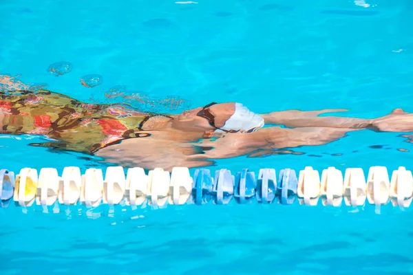 穿着泳衣在蓝色游泳池上游泳的女人 — 图库照片