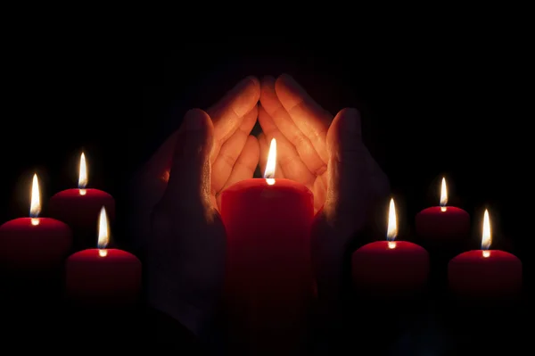 Dwie ręce oświetlone przez świeca w ciemności — Zdjęcie stockowe