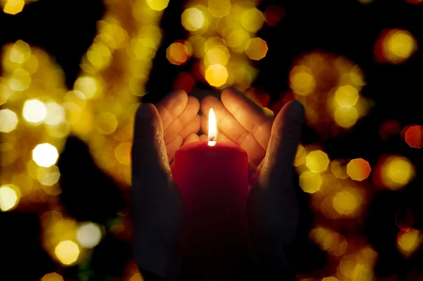 Zwei von einer Kerze erleuchtete Hände in der Dunkelheit — Stockfoto