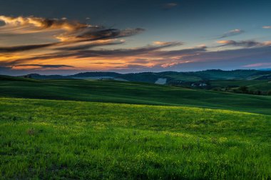 Toskana baharı, yuvarlanan tepeler ve gün batımında yel değirmeni. Kırsal alan. Yeşil alanlar. İtalya, Avrupa