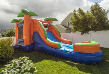 Inflatable bounce house water slide in the backyard clipart