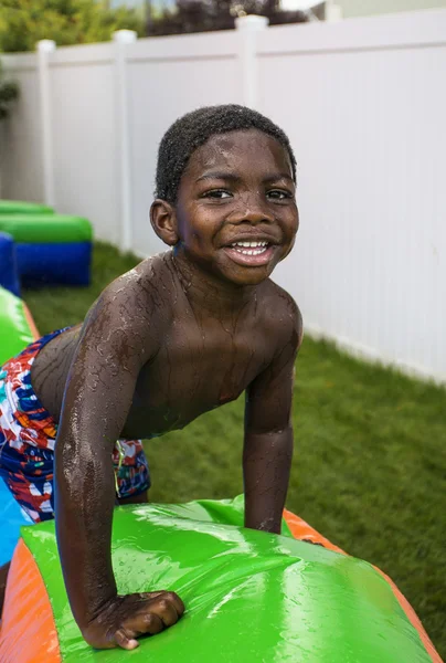 Sorrindo menino brincando ao ar livre em uma casa de salto inflável . — Fotografia de Stock