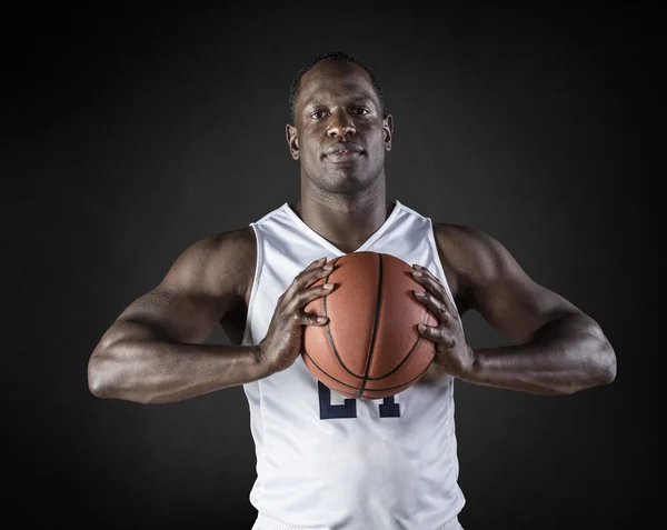 African American Basketball Player portrait holding a ball. Black background — Stock Photo, Image