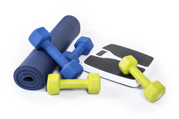 Fitness and weight loss equipment isolated on a white background. A yoga mat, dumbbell weights and a weight scale all together — Stock Photo, Image