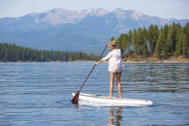 Güzel kadın paddleboarding doğal dağ Gölü üzerinde