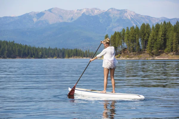 Mooie vrouw paddleboarding op schilderachtige bergmeer — Stockfoto