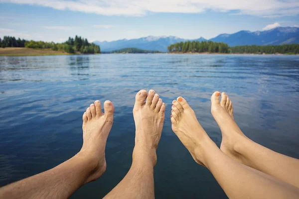 美しい山の湖岸にリラックスしたカップル。自分の足と足の指見ての視点. — ストック写真