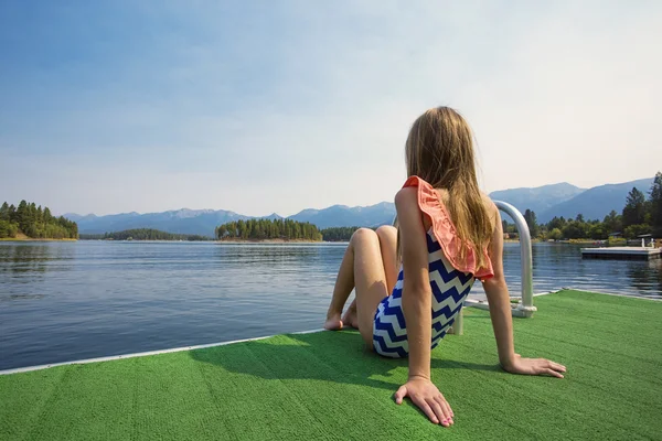 Little girl sitting on a dock — Stock Photo, Image