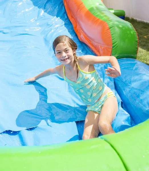 Sonriente niña jugando en una casa inflable de la despedida de la diapositiva — Foto de Stock