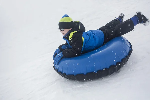 雪に覆われた丘を下ってそり滑り少年の雪 — ストック写真