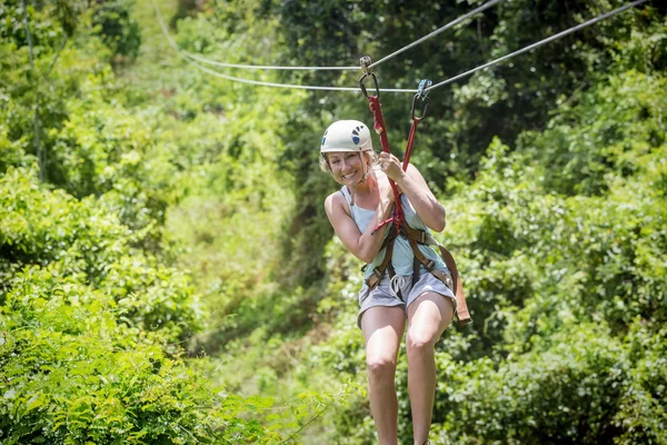 Beautiful woman riding a zip line — Stock Photo, Image