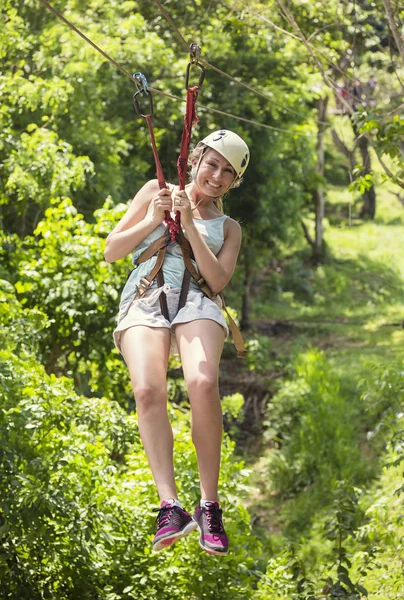 Beautiful woman riding a zip line — Stock Photo, Image