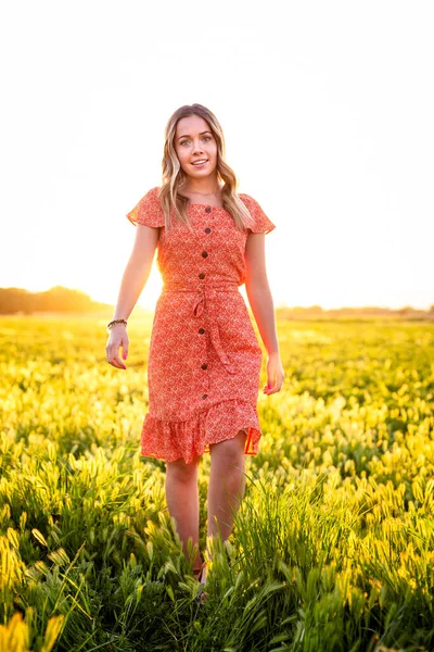 花の分野における赤いドレスの美しい若い女性の肖像画 — ストック写真