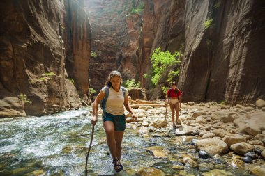 Taşlarla çevrili nehri geçen turistler