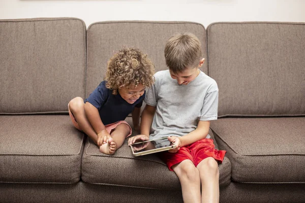 Χαρούμενα Μικρά Παιδιά Που Χρησιμοποιούν Tablet Ενώ Κάθονται Στον Καναπέ — Φωτογραφία Αρχείου