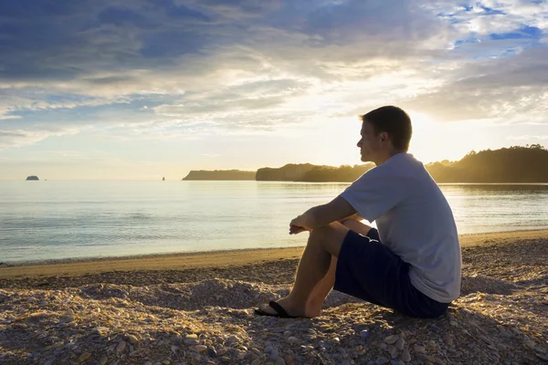 Homem desfrutando de um pôr do sol na praia — Fotografia de Stock