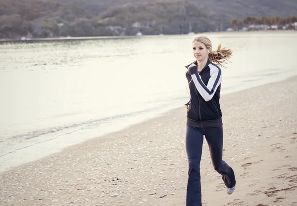 Jeune femme courant le long de la plage — Photo