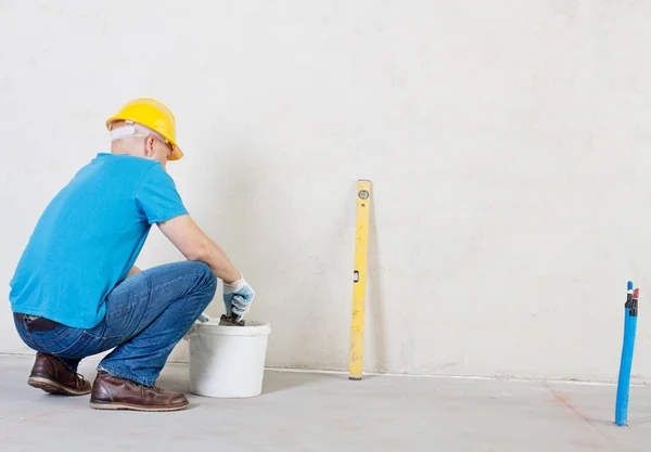 Stukadoor man met Troffel en emmer in de buurt van de pleister muur. — Stockfoto