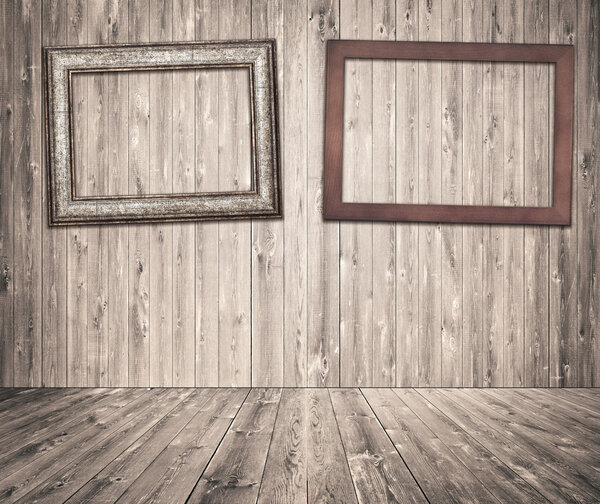 Wooden picture frames hanging on gray planks wall with old pine, fir floor