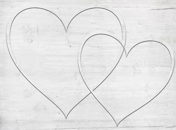 Dos corazones de madera colocados en una tabla de madera blanca — Foto de Stock