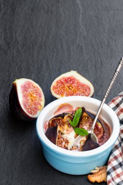 Pişmiş incir keçi peyniri ve ballı ceviz, siyah taş arka planda. 