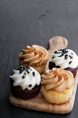 Tahtada, siyah taş zemin üzerinde mini kekler. 