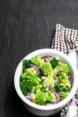 Siyah taş arka planda kapari ve soğan salatası ile Romanesco karnabahar 