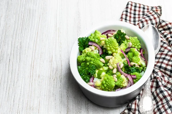 Beyaz ahşap masada kapari ve soğan salatası ile Romanesco karnıbaharı. 