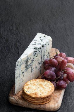 Siyah taş arka planda üzümlü ve krakerli Gorgonzola peyniri 