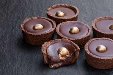 Taş zeminde altın damlalarla süslenmiş erimiş çikolatalı karamel trüf mantarları 